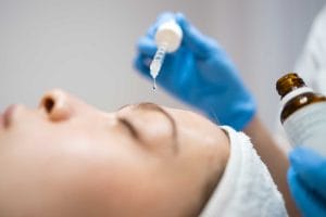 Professional administering facial treatment with serum