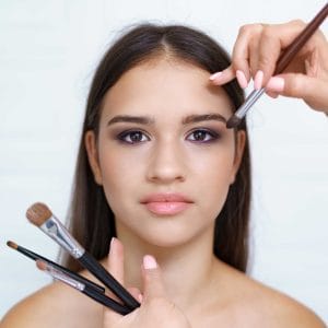 Makeup artist applying cosmetics on young woman's face