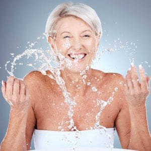Joyful senior woman splashing water, laughing