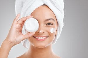 Woman applying moisturizer with towel on head