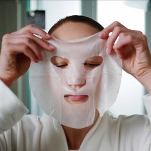 Woman applying facial skincare mask indoors