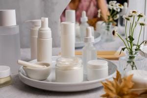 Assorted skincare products on a tray beside flowers.