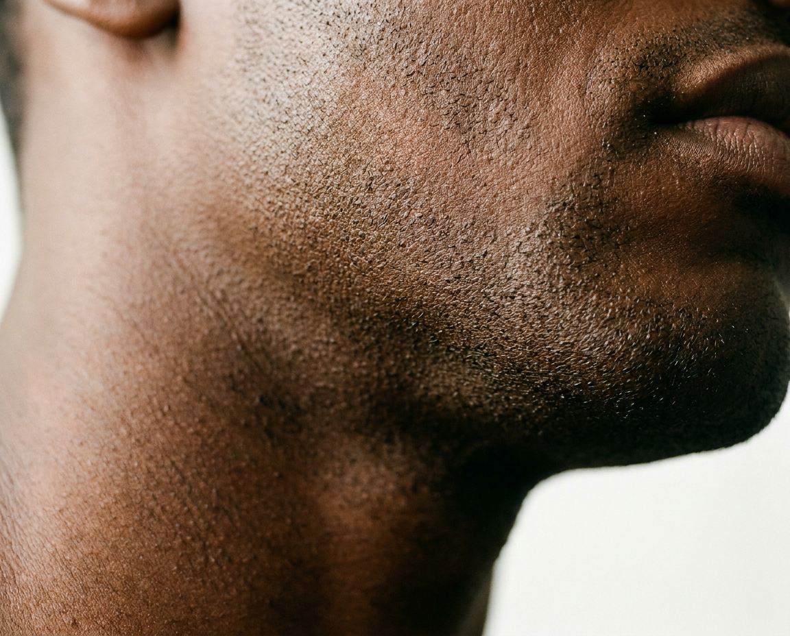 Close-up editorial shot of a man's jawline and neck showing clear post-shave skin with stubble texture