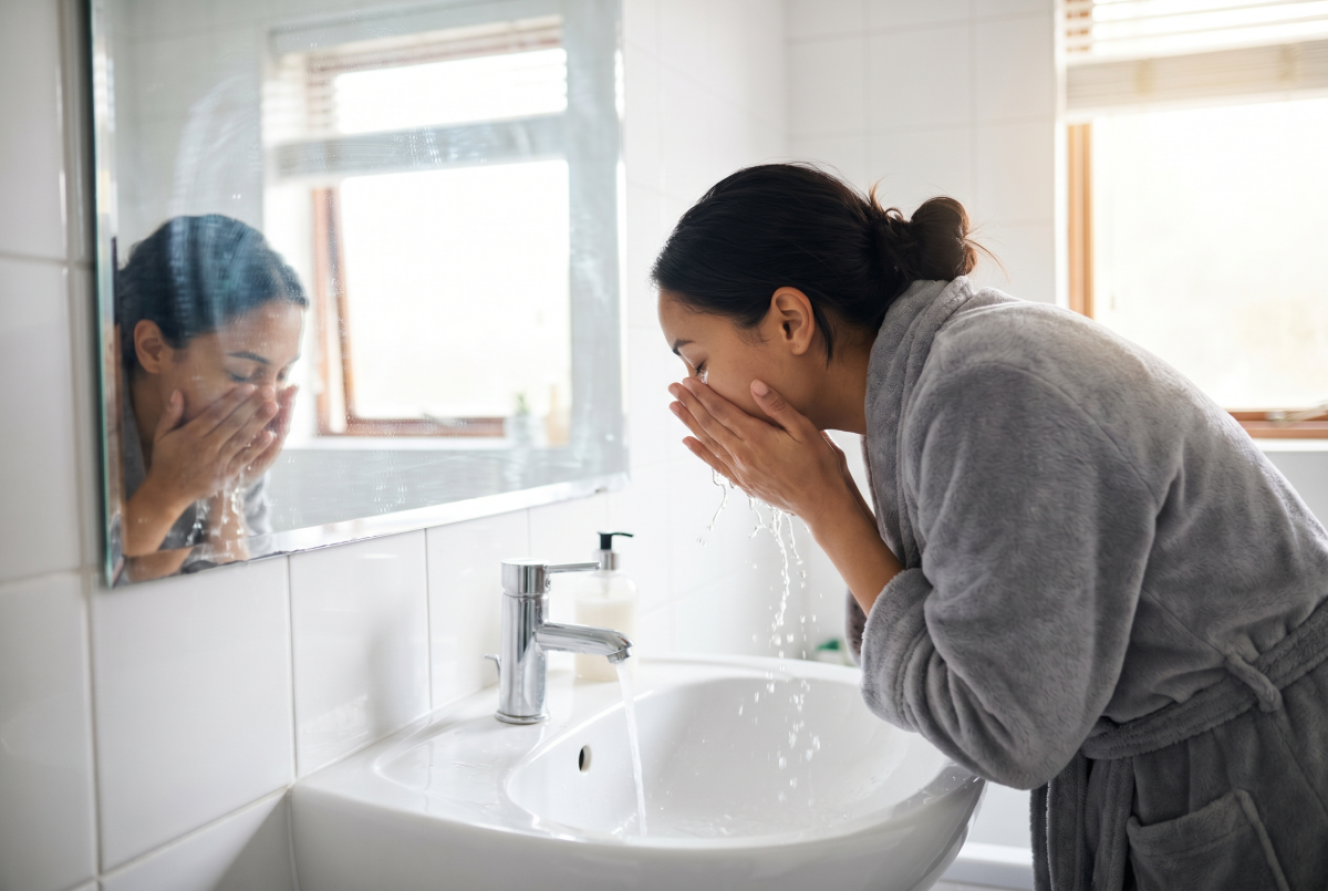 Woman washing face at bathroom sink