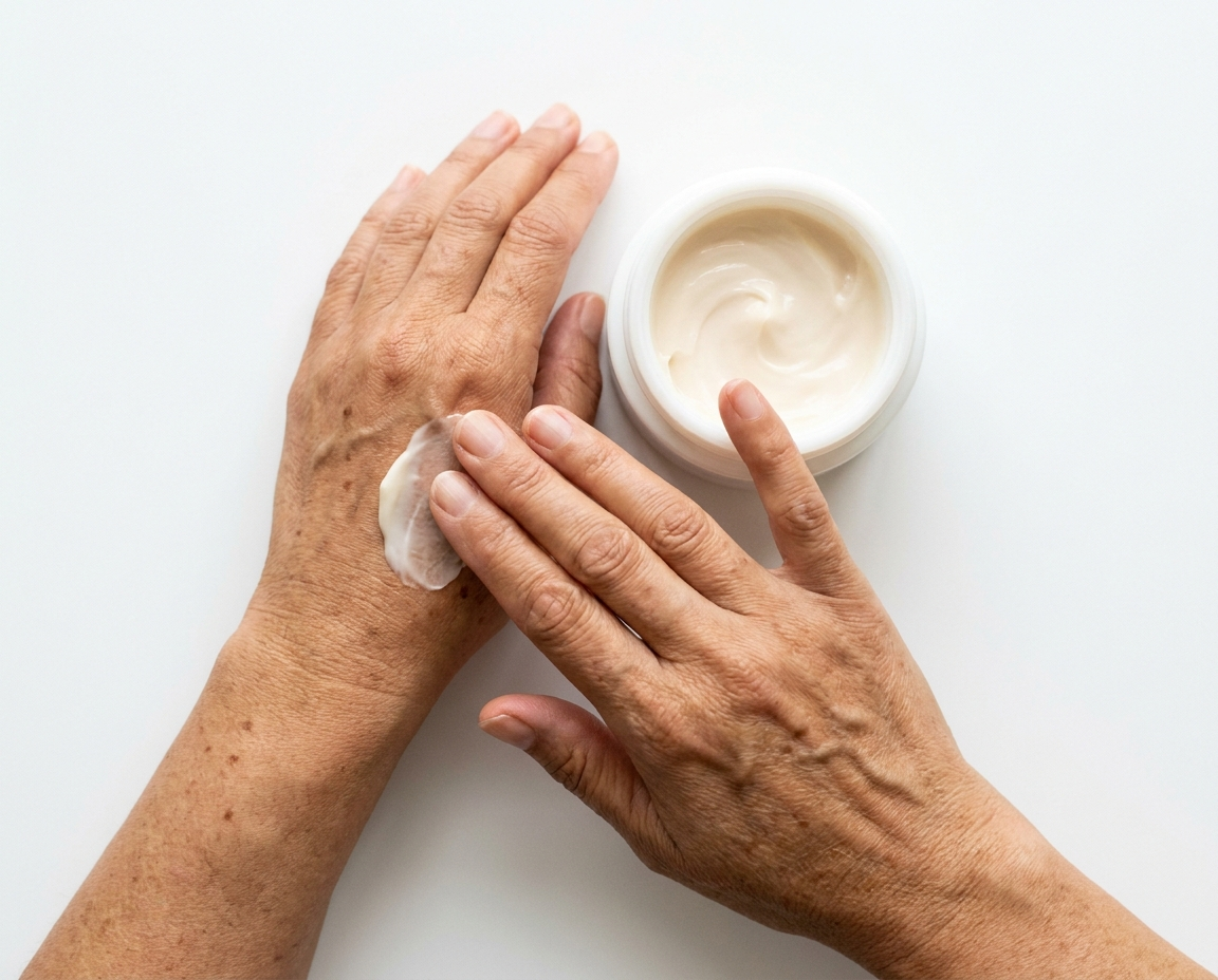 Close-up overhead shot of olive-toned hands smoothing cream from a simple white jar