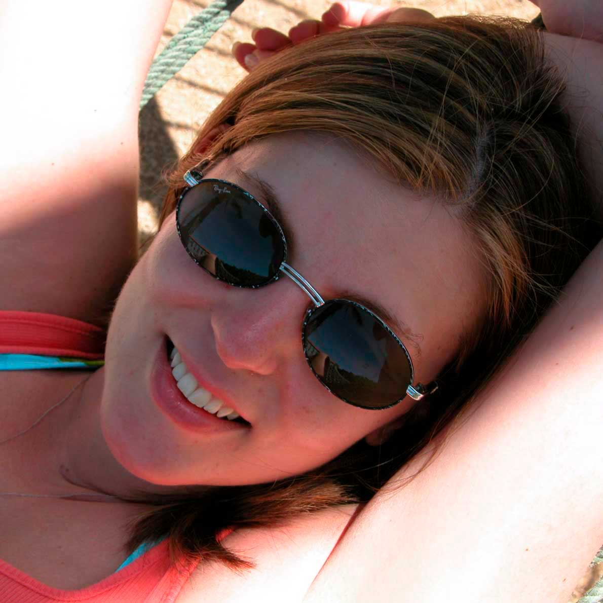 Smiling woman relaxing outdoors in round sunglasses